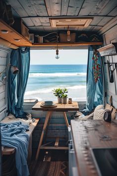 the inside of a camper van with blue curtains and a table in front of it