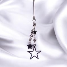 a pair of black stars hanging from a hook on a white satin background with beads