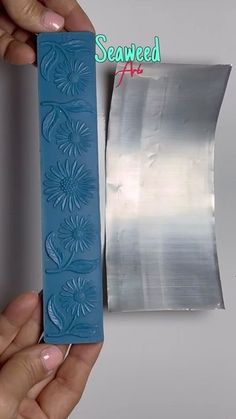 a person is holding a piece of blue paper with flowers on it and the other side has a roll of duct tape