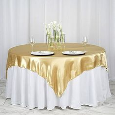 the table is set with two wine glasses and three plates on it, along with flowers in vases