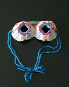 a mask with blue string attached to it on a black surface next to a pair of eyeglasses