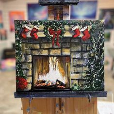 an easel with a painting on it in the shape of a fireplace decorated for christmas