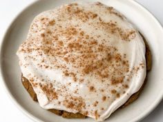 a white plate topped with a cookie covered in frosting and cinnamon sprinkles