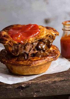 a meat pie sitting on top of a piece of paper next to a jar of ketchup