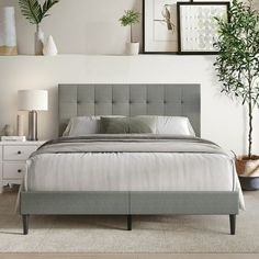 a bedroom with a bed, nightstands and pictures on the wall above it that are displaying potted plants