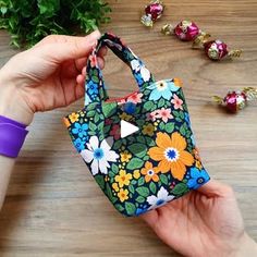 a hand holding a small purse on top of a wooden table next to some candy