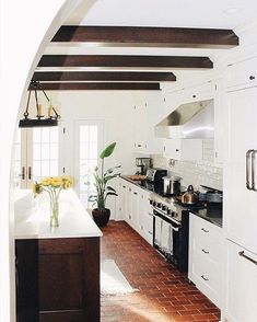 an arched doorway leads to a kitchen with white cabinets and wood floors, along with a center island