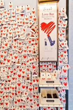 a wall covered in lots of red and white heart shaped magnets next to a sign that says fresh love bar