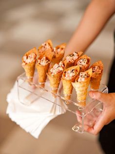 a person holding a tray with cones filled with food