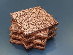 four pieces of wood are stacked on top of each other in order to be used as coasters