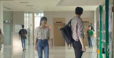 two young women walking down a hallway with backpacks on their back and one carrying a book bag