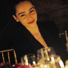 a woman sitting at a table with wine glasses in front of her and candles on the table