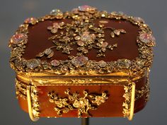 an elaborately decorated wooden box with gold trimmings and jewels on it's sides