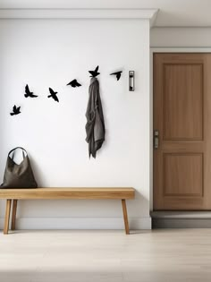 there is a bench and coat rack in this room with birds on the wall above it