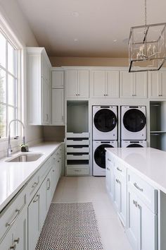 a white kitchen with two washers and a dryer in the middle of it