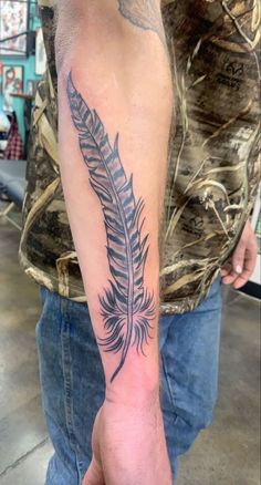 a man with a feather tattoo on his arm