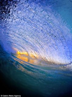 the inside of a wave with blue water and yellow light coming from it's center