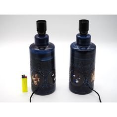 two black bottles with designs on them next to a yellow lighter