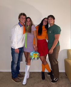 four people posing for the camera in front of a wall