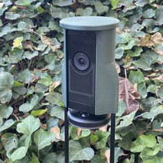 a camera sitting on top of a metal stand in front of some plants and leaves