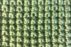 close up view of the texture of a knitted fabric with green and white colors