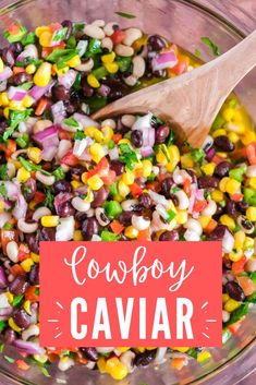 a bowl filled with black beans, corn and cilantro next to a wooden spoon