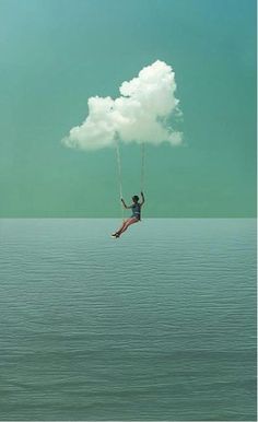 a person on a swing suspended from a cloud above the water with a sky background