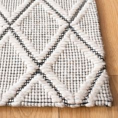 a white and black area rug on a wooden floor with a wood floor in the background