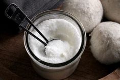 a glass jar filled with white powder next to three balls of bread