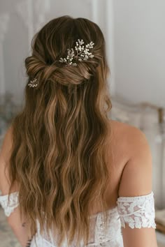 a woman with long brown hair wearing a white top and some flowers in her hair