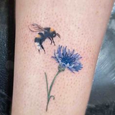 a tattoo with a bee on the side of it and a flower in front of it