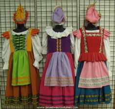 three children's dresses hanging on a wall