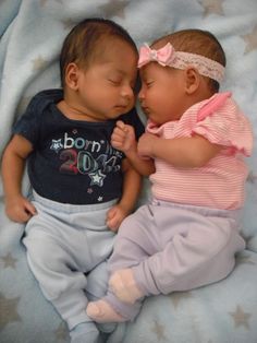 two babies laying next to each other on top of a blue blanket covered in stars