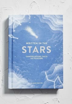 the book written in the stars is sitting on top of a white wall and it's blue cover