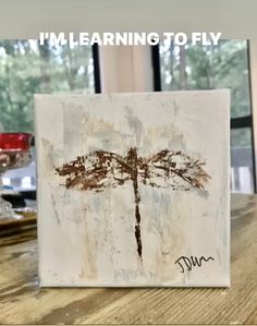 a painting on a wooden table with the words i'm learning to fly above it