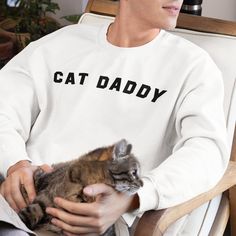 Hey there, Cat Daddy.  This cat daddy long sleeve crewneck sweatshirt is a great gift for Cat Owners. Makes a great present for the cat lover in your life's Birthday, Mother's Day, Father's Day, Christmas, Valentine's Day, Graduation, Kitty Adoption Anniversary or just for a cat daddy who loves their floof. The sweatshirt is: * Gildan brand Unisex crewneck (sizing in pictures). I've personally tested this sweatshirt over the years and it holds up great to washings and doesn't warp or lose it's fit.  * Pre-shrunk * 50% cotton, 50% polyester * Classic fit with no center crease If you have any questions or comments, feel free to message me anytime. Adoption Anniversary, Best Cat, Cat Owners, Cat Gifts, Cat Lover, Crewneck Sweatshirt, Cat Lovers, Father's Day, Adoption