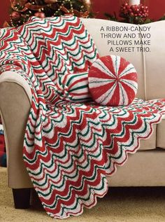 a red and green afghan sitting on top of a couch next to a christmas tree