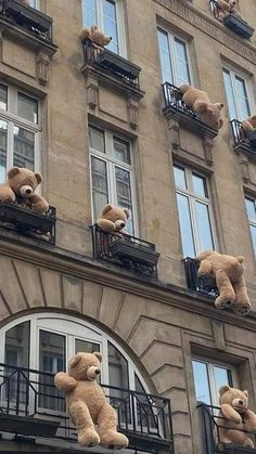 teddy bears are on the balconies of an apartment building