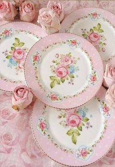 pink roses are on the table with white plates