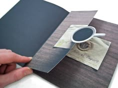 a hand is holding an open book with a cup of coffee on the front cover