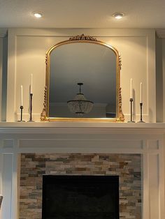 a fireplace with a mirror above it and candles in front of the fire mantel