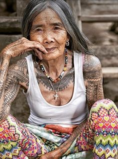 an old woman with tattoos sitting on the ground