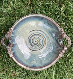 a bowl sitting in the grass on top of it's side with a spiral design