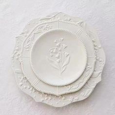 three white plates sitting on top of a table next to each other in front of a white wall