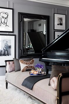 a living room with a couch, piano and pictures on the wall in it's corner