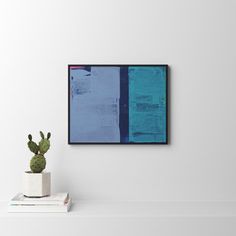 a cactus sits on top of books in front of a white wall with a blue painting