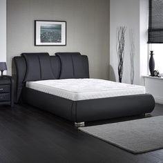 a black bed frame in a room with hardwood floors