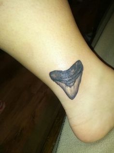 a small foot with a shoe tattoo on it's left side leg and the bottom part of the foot visible