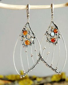 the earrings are made with silver wire and glass beaded beads, on top of a branch