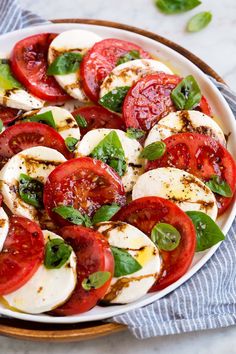 a white bowl filled with sliced tomatoes and mozzarella cheese on top of a blue towel